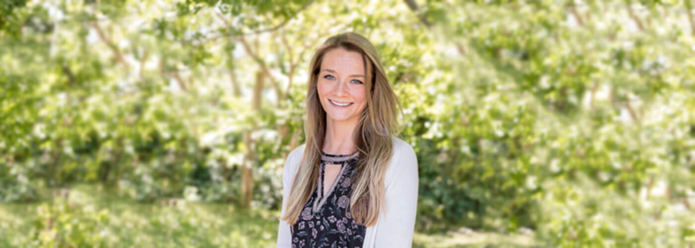 Lifestyle Director, Kristin Kullberg, posed in front of a wooded area smiling at the camera.