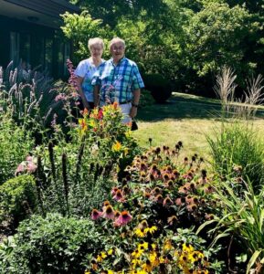 Older couple standing outside in their beautiful garden.