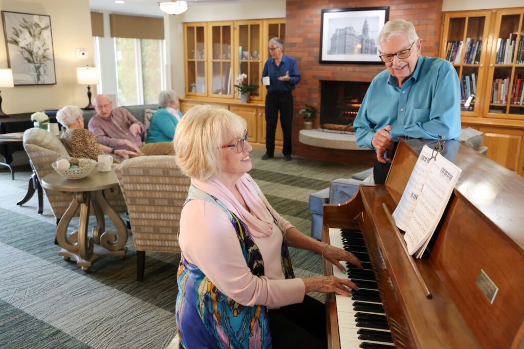 woman playing piano with a man watching
