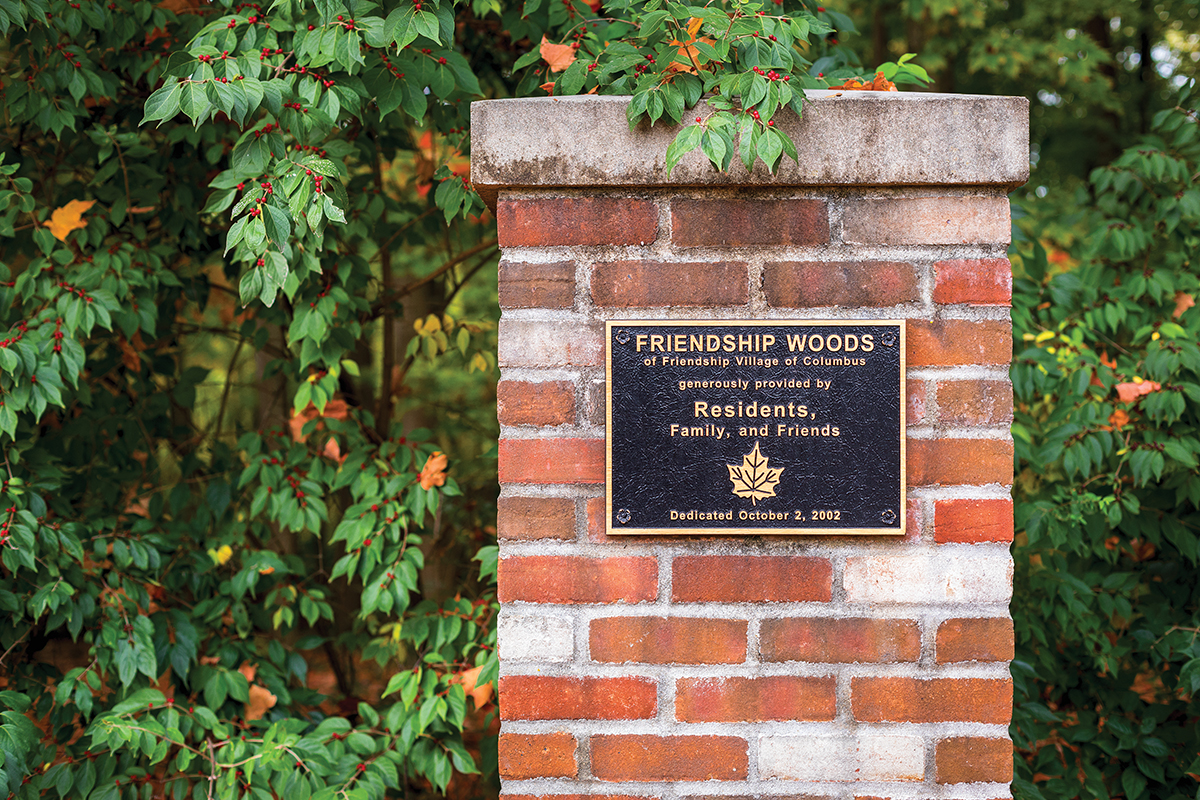 The Friendship Woods plaque on a brick pillar marking the entrance to the woods.