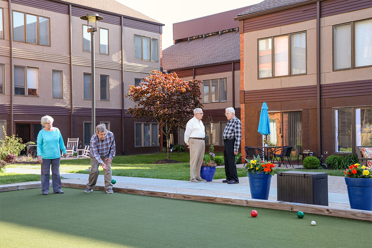 Group of friends playing bocce ball outside.