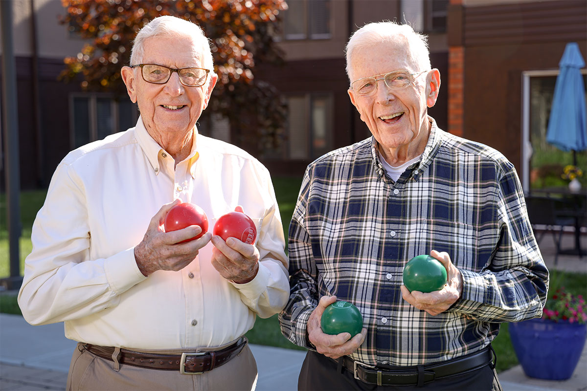 Two friends holding bocce balls as they get ready for a game.