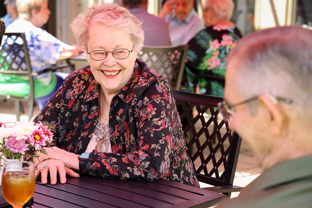 Woman smiling at her husband while seated outside at a table at Westerwood.