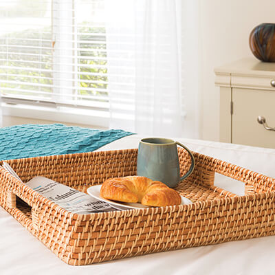 newspaper, croissant, and coffee mug in woven serving tray