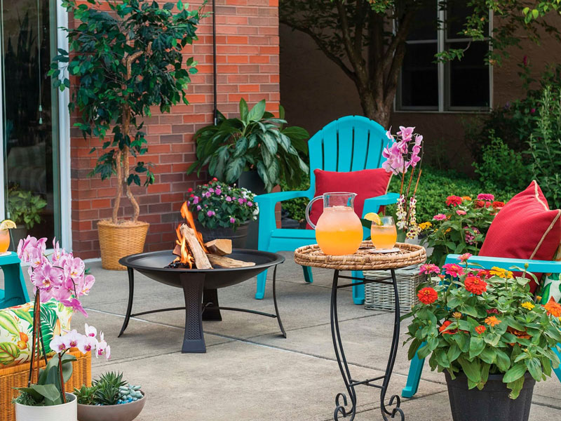 spacious outdoor patio with small firepit and lots of potted plants