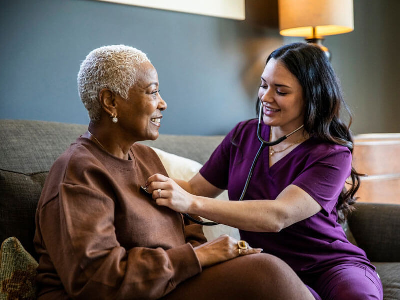 nurse listening to a mature woman's heartbeat