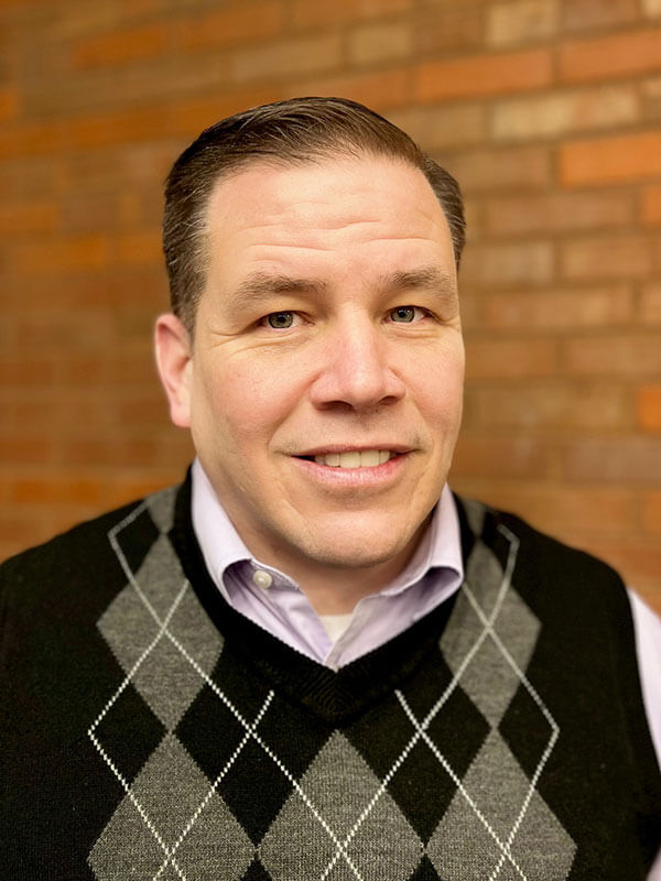 portrait of a person wearing a light-colored dress shirt