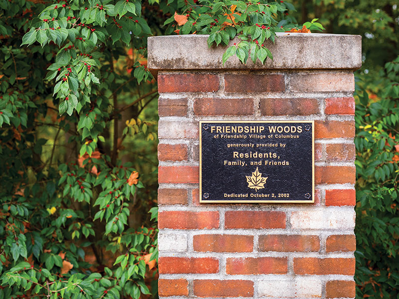 brick pillar with a plaque that reads "Friendship Woods of Friendship Village of Columbus"