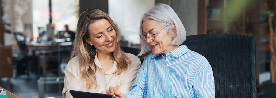 Two women at a table, collaborating on a tablet
