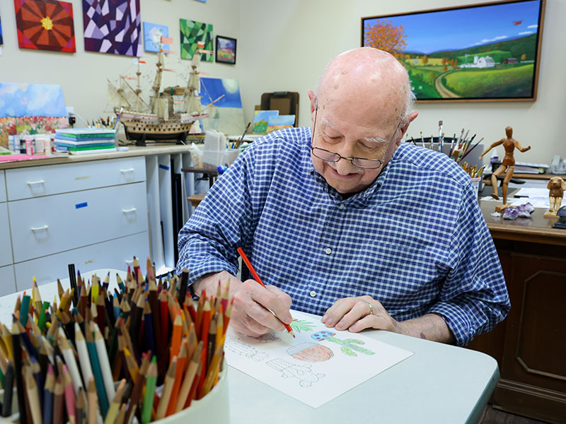 elder man drawing a picture with colored pencils