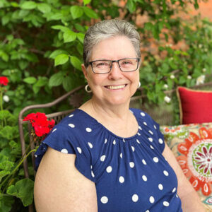 An older women with glasses smiles warmly at the camera