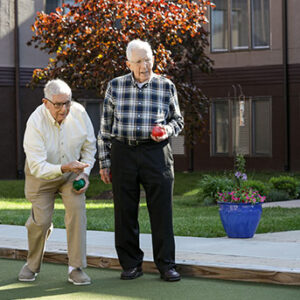 Two men playing bocce ball on a green lawn