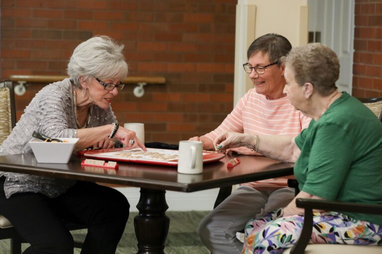 Three adults are seated around a square table