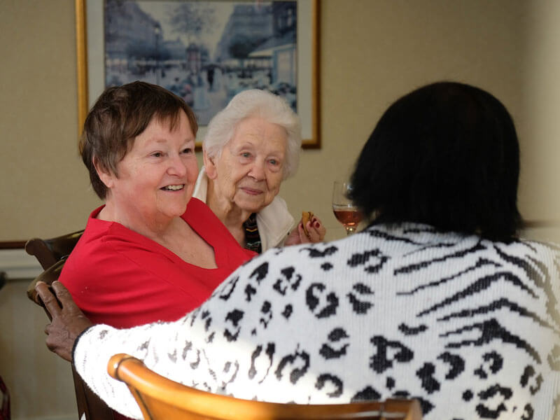 three residents at Westerwood engaging in conversation at a table